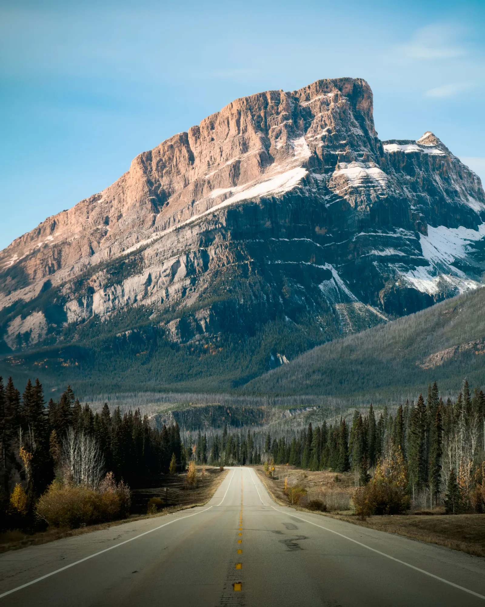 The Icefields Parkway running toward a steep mountain face.