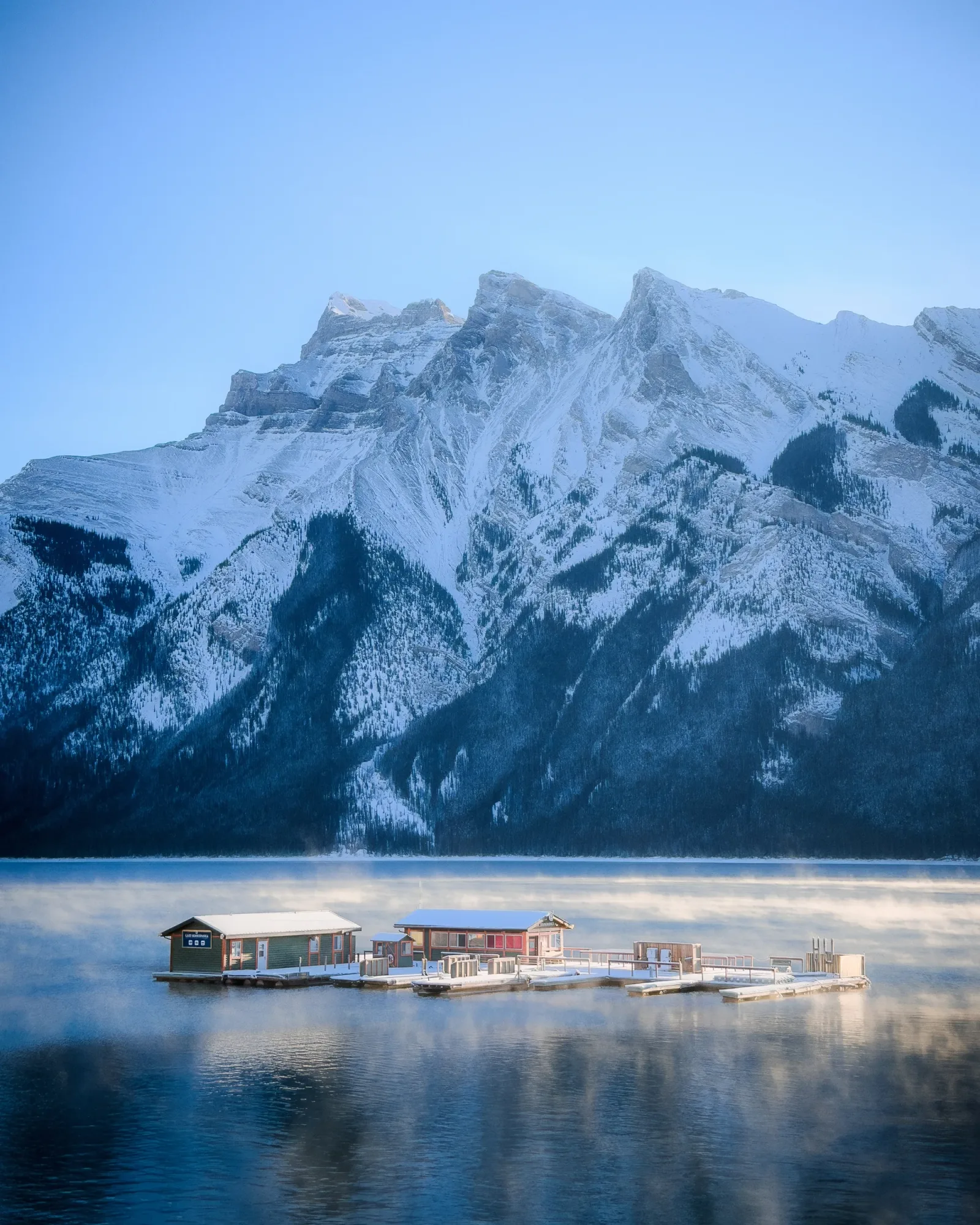A small lakeside cabin below snowy Mount Rundle.