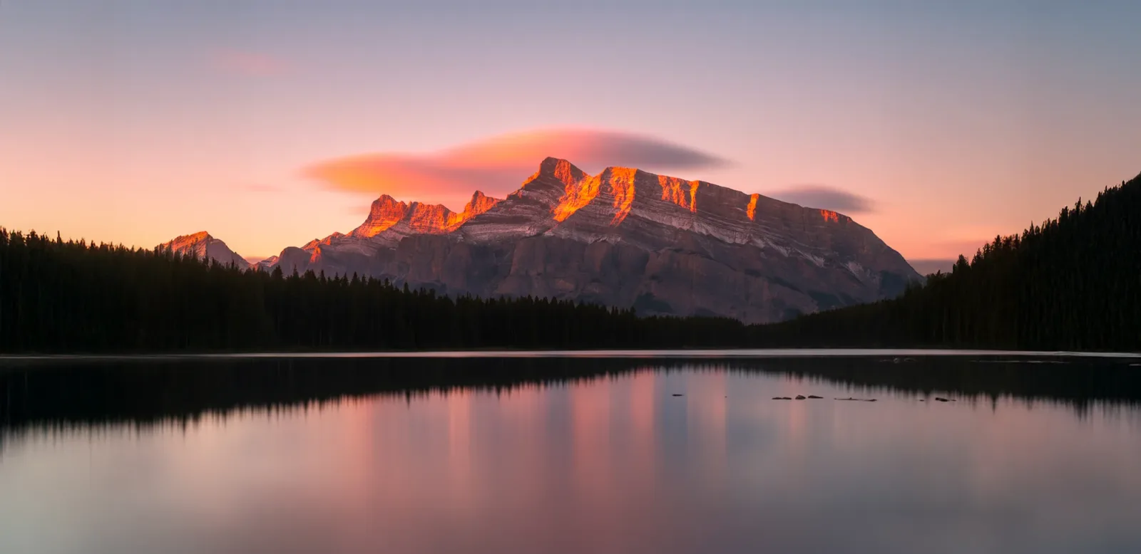 Mount Rundle glowing pink above Two Jack Lake at dawn.