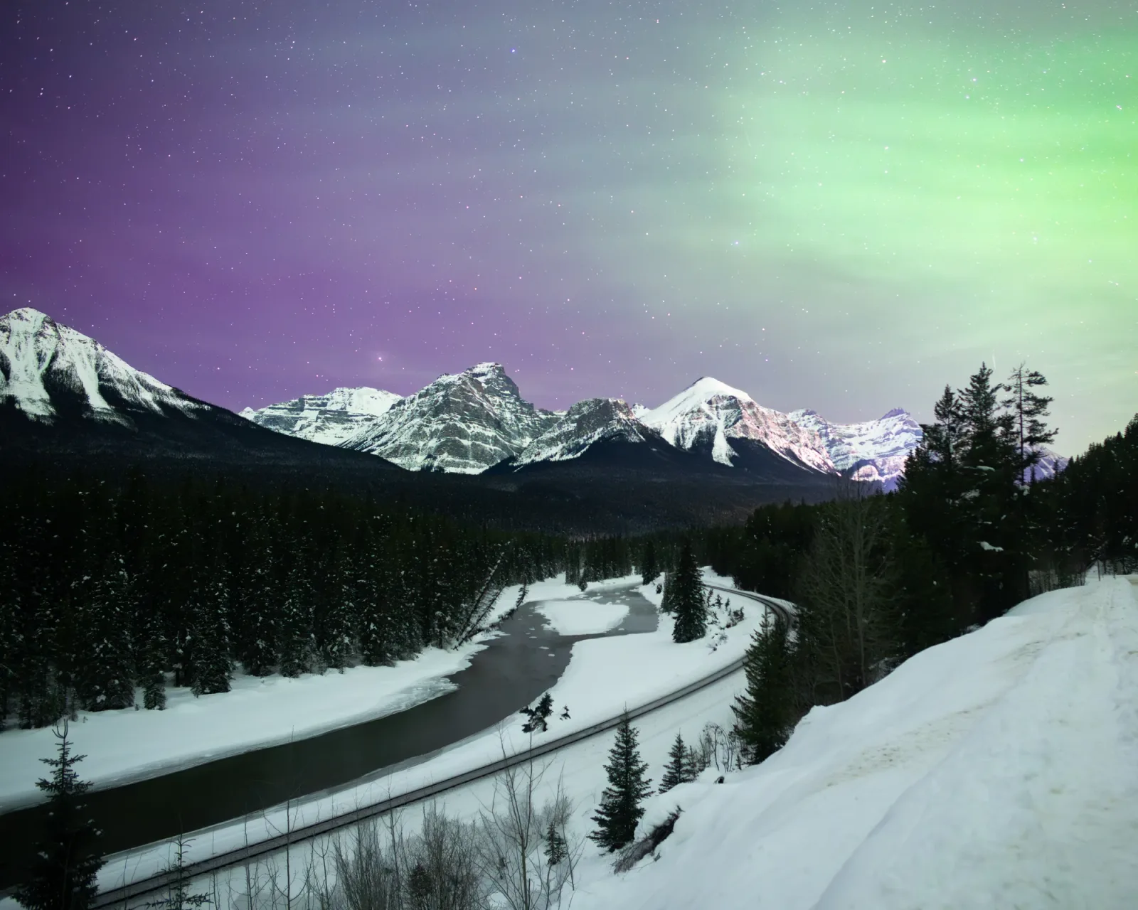 A snow-lined mountain road beneath a night sky.
